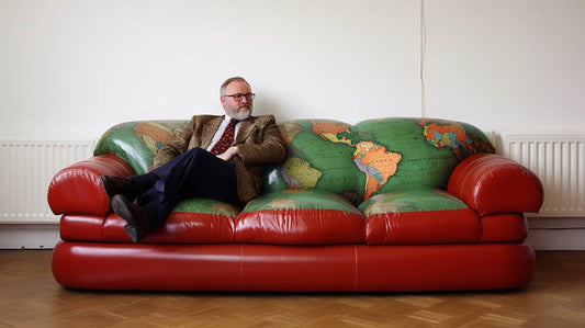 A sofa for every person red sofa with green map and a professor sitting on it
