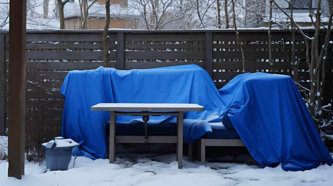 Outdoor furniture and cushions being stored under a sheet in the winter with snow on the ground