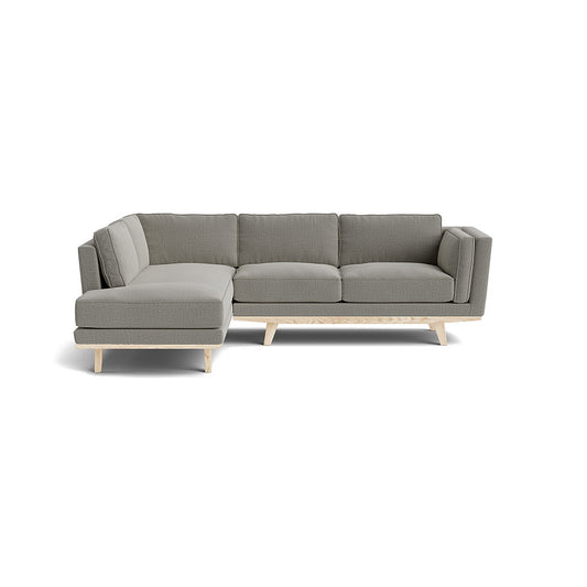 The Kirnik Bumper Sectional in Natural Latex is a modern L-shaped sofa featuring light gray upholstery and light wood legs, beautifully set against a plain white background.