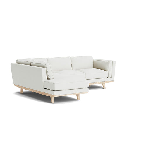 The Kirnik Bumper Sectional in Natural Latex is a modern L-shaped sofa featuring light cream upholstery and wooden legs, set against a plain white background.