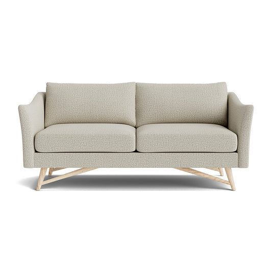 The Gio Sofa in Natural Latex is a modern, light gray sofa with two cushions and wooden legs set against a white background. It boasts textured fabric and slightly curved armrests.