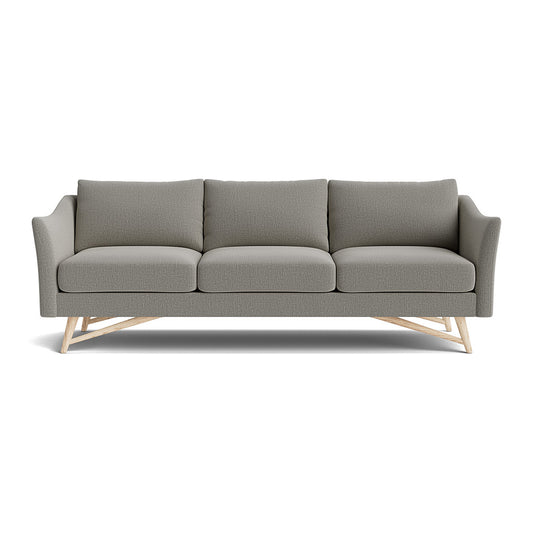 Experience the comfort of the Gio Sofa in Natural Latex, a modern gray three-seat piece featuring a wooden frame and angled legs, plush cushions, and elegantly curved armrests.