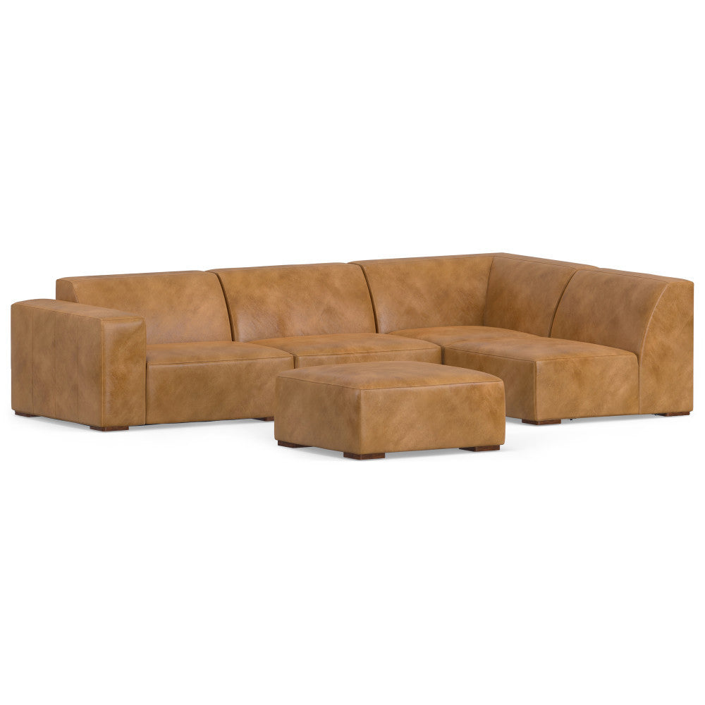 A large, tan, L-shaped leather sectional sofa with a matching ottoman. The design is modern and minimalist, featuring smooth surfaces and wide, low-profile arms. The set is arranged on a white background.