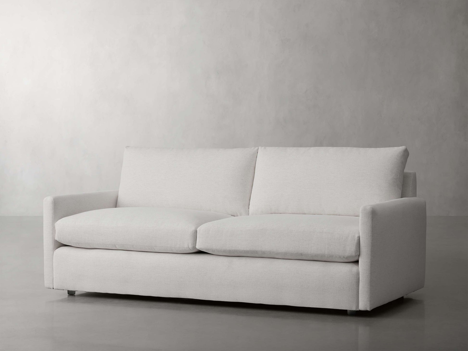 The Kipton 84" Deep Sofa, in a modern white design with clean lines, is set against a plain, light gray background. It boasts a simple aesthetic with two seat cushions and two backrest cushions, delivering a minimalist and contemporary appearance.