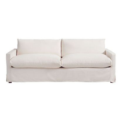 The Brynn Feather-Filled Sofa is showcased against a white backdrop, featuring a plush, minimalist design in off-white. It includes two large seat cushions and two back cushions, complemented by straight arms and a skirted base for a clean aesthetic.