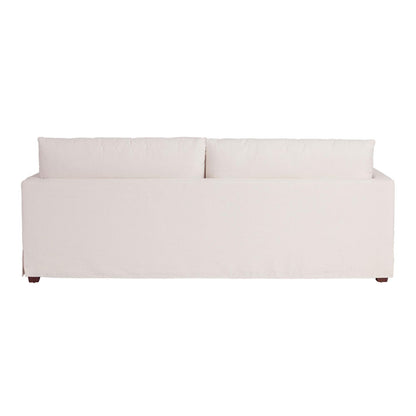 The Brynn Feather-Filled Sofa features a cream-colored, minimalist design when viewed from the back. It has two large back cushions and lacks visible armrests, with its wooden legs subtly showing underneath. The fabric boasts a smooth texture.