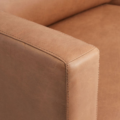 Close-up of a corner of the Abrie Vintage Tan Leather Sofa, highlighting the stitching and texture of the material. The sofa features a smooth, matte finish and appears comfortable and sturdy.