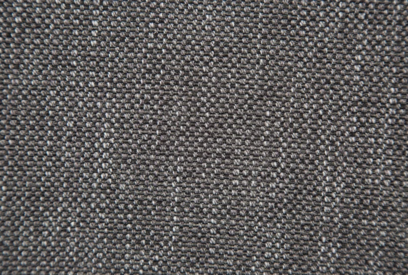 Close-up of the textured gray fabric on the Talin Power Reclining Sofa with USB, showcasing a detailed view of the finely woven pattern. The interlacing threads create a uniform and slightly speckled appearance.