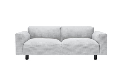 The Koti 2-seater Sofa is a contemporary loveseat in light gray with textured fabric and straight armrests, supported by four short black legs, against a plain white background.