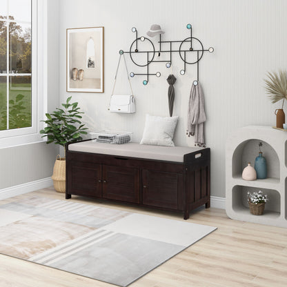 A modern entryway features a cushioned Storage Bench with 3 shutter-shaped doors. Above, a wall rack holds hats and a bag. A potted plant stands by the bench, next to a light shelf displaying decor items, while a large window lets in natural light.