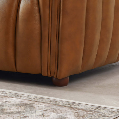 Close-up of the corner of the April Mid-Century Modern Luxury Tight Back Boucle Couch, featuring a wooden leg and vertical seam detail, placed on a decorative rug with intricate patterns.