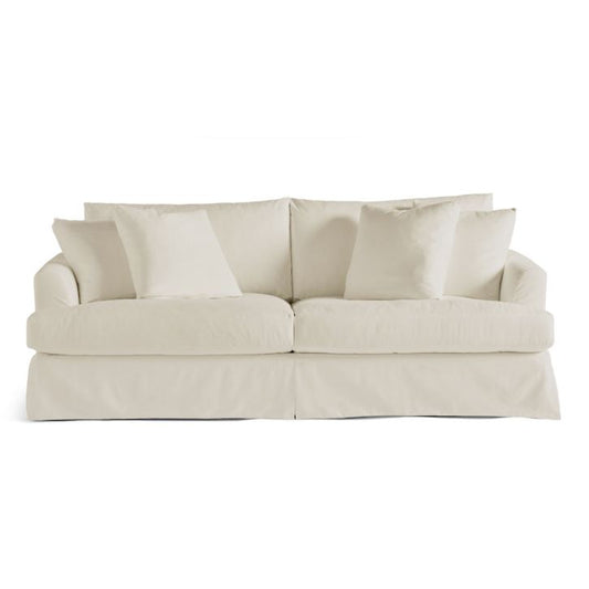 From a front view, the Ava Slipcovered Sofa showcases its plush, cream-colored design. With its soft, oversized cushions and relaxed style, it exudes coziness and an inviting charm. The sofa is adorned with four matching cushions for added comfort.