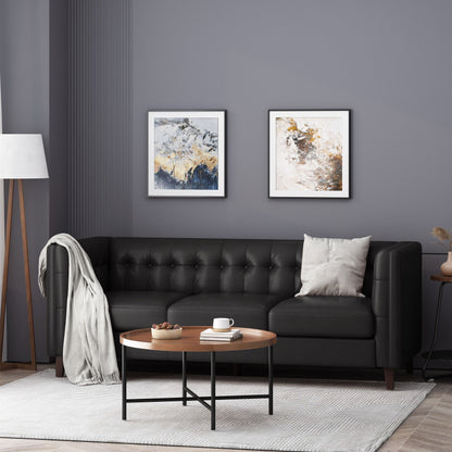 A modern living room featuring a Comfy 3 Seat Sofa with tufted back, draped with a light throw and cushion. A round coffee table displays books and decor, while two abstract paintings enhance the gray wall above. A tall floor lamp is positioned to the side.