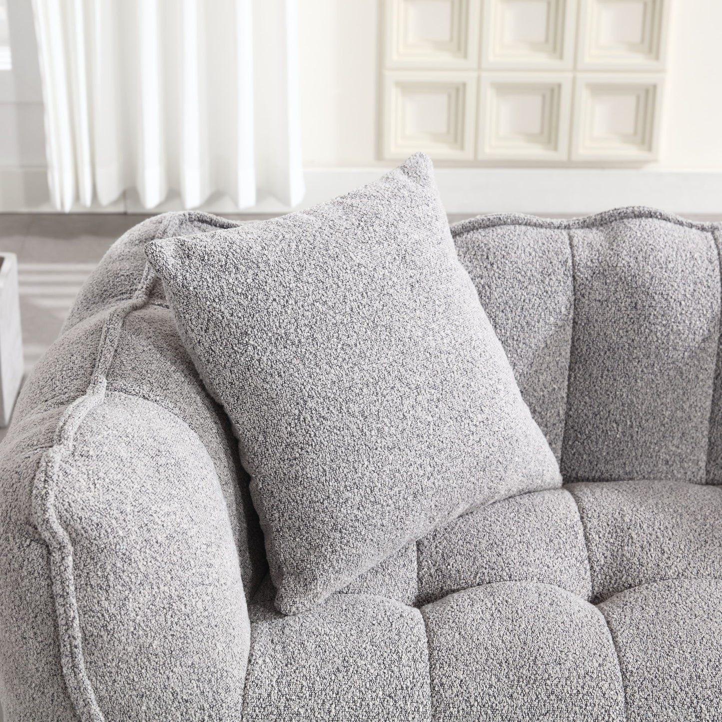 The setting includes a Soft Beanbag Chair with a high resilience foam core for two people, accompanied by textured fabric cushions. A white curtain and paneled wall in the backdrop create a soft and elegant ambiance.