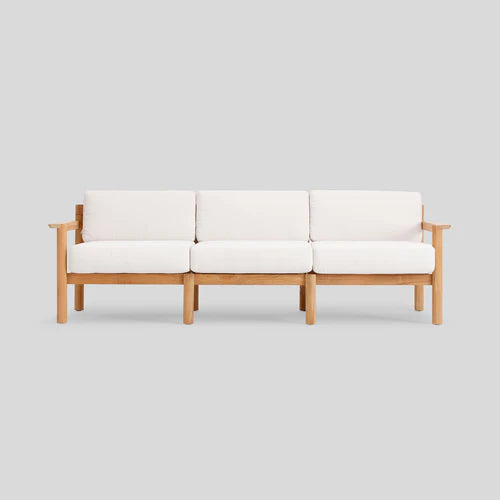 The Haven Sofa is a minimalist wooden piece featuring three cushioned seats and backrests in white, set against a plain grey background. It showcases a simple, modern design with straight armrests.