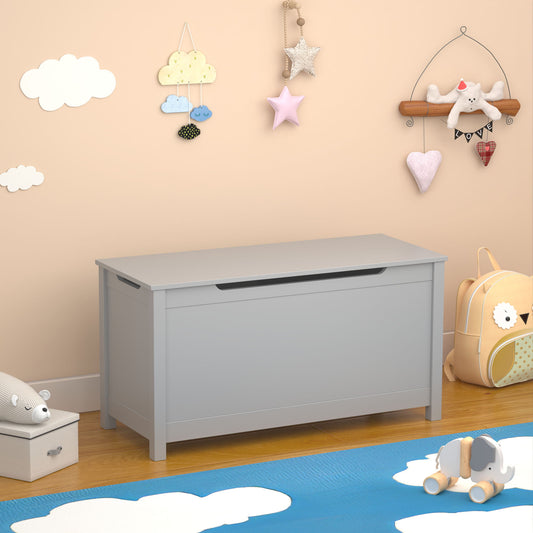 A beige nursery wall with cloud and star motifs accompanies a gray Kids Wooden Toy Box Storage with a safety-hinged lid for ages 2+. A wooden shelf holds soft toys, a blue rug with white clouds covers the floor, and nearby are a backpack and stackable blocks.