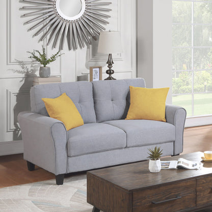 A cozy living room showcases a light gray Modern Living Room Loveseat Linen Upholstered Couch with two yellow throw pillows. A radiating-design circular mirror hangs behind, a lamp sits on a side table, and a wooden coffee table holding a small plant is in front, while the window opens to a green landscape.