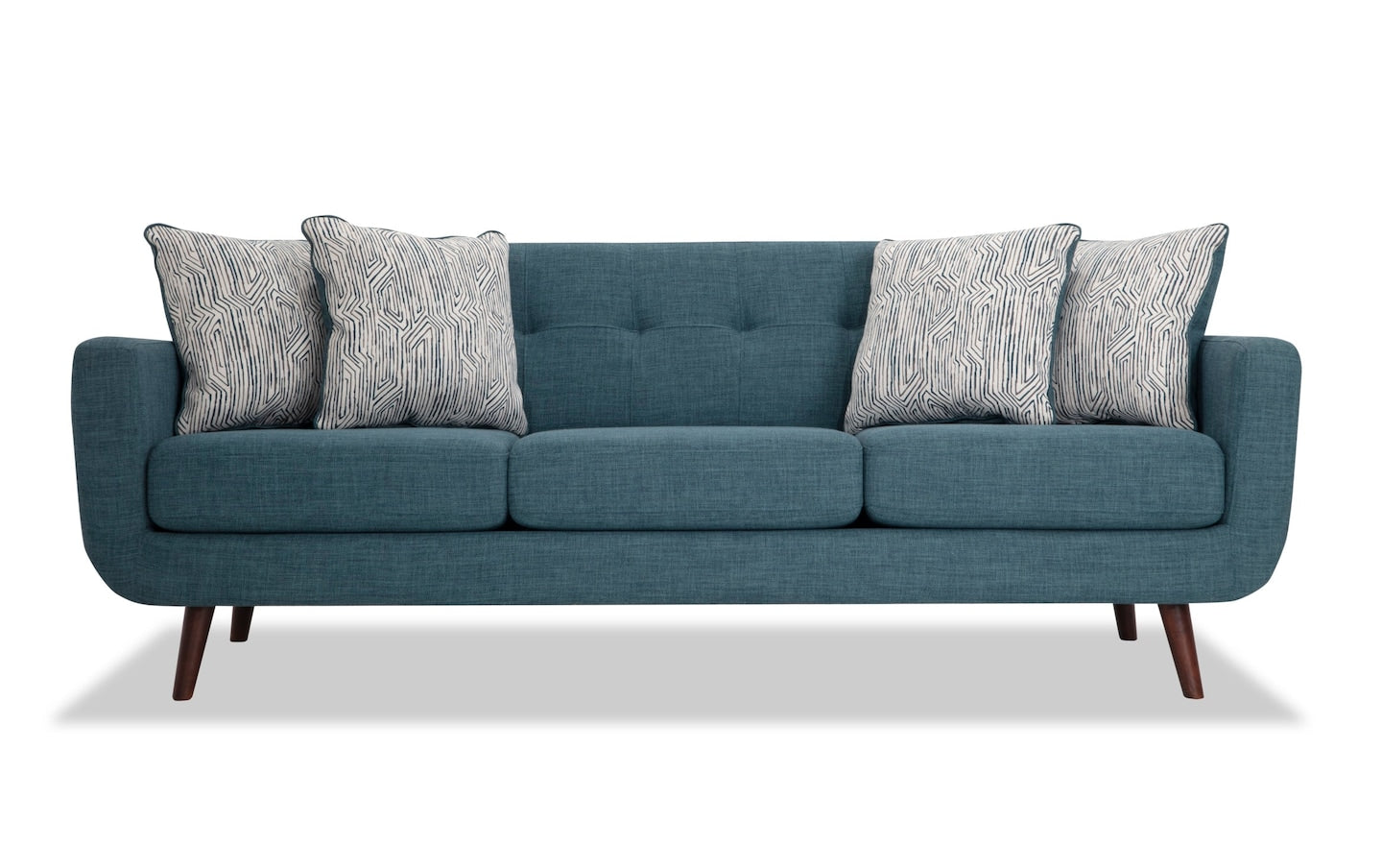 The Bettie 86'' Sofa is a modern teal piece with three cushions and wooden legs, complemented by four patterned throw pillows in a black and white design, all showcased against a plain white background.