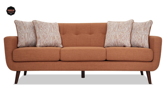 The Bettie 86'' Sofa is a modern piece featuring an orange-brown color with three seat cushions and patterned throw pillows. It boasts wooden legs and a tufted backrest, offering a stylish and comfortable appearance.