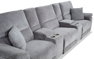 The Renegade Gray 125'' Power Reclining 6 Piece Sectional with USB Port features a spacious and plush design in a soft gray fabric, complete with two convenient cup holders and several matching cushions, making it perfect for lounging or creating a cozy home theater environment.