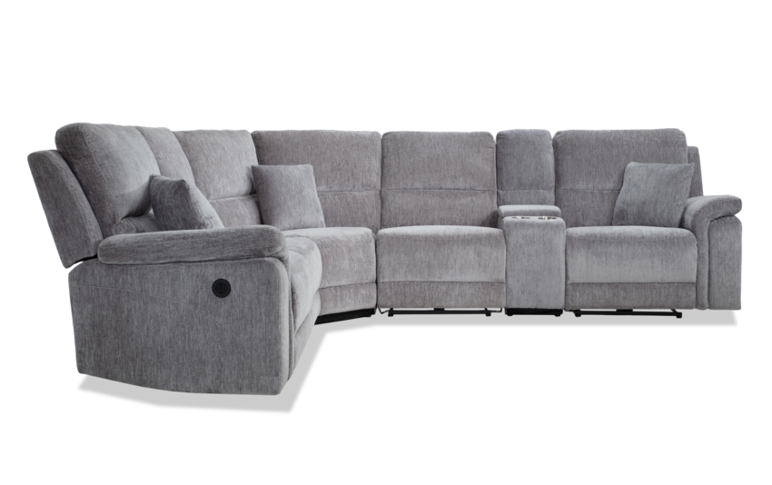 A spacious Renegade Gray 125'' power reclining sectional featuring plush cushions and multiple throw pillows. The six-piece configuration includes a corner seat, central console with cup holders, and USB port, all wrapped in a soft and comfortable fabric.