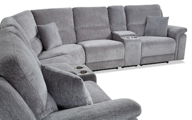 The Renegade Gray 125'' Power Reclining 6 Piece Sectional, featuring plush and soft upholstery, offers an L-shaped design in a large size. It includes two built-in cup holders and comes with a matching throw pillow on one of the seats, making it perfect for a cozy living room setting.