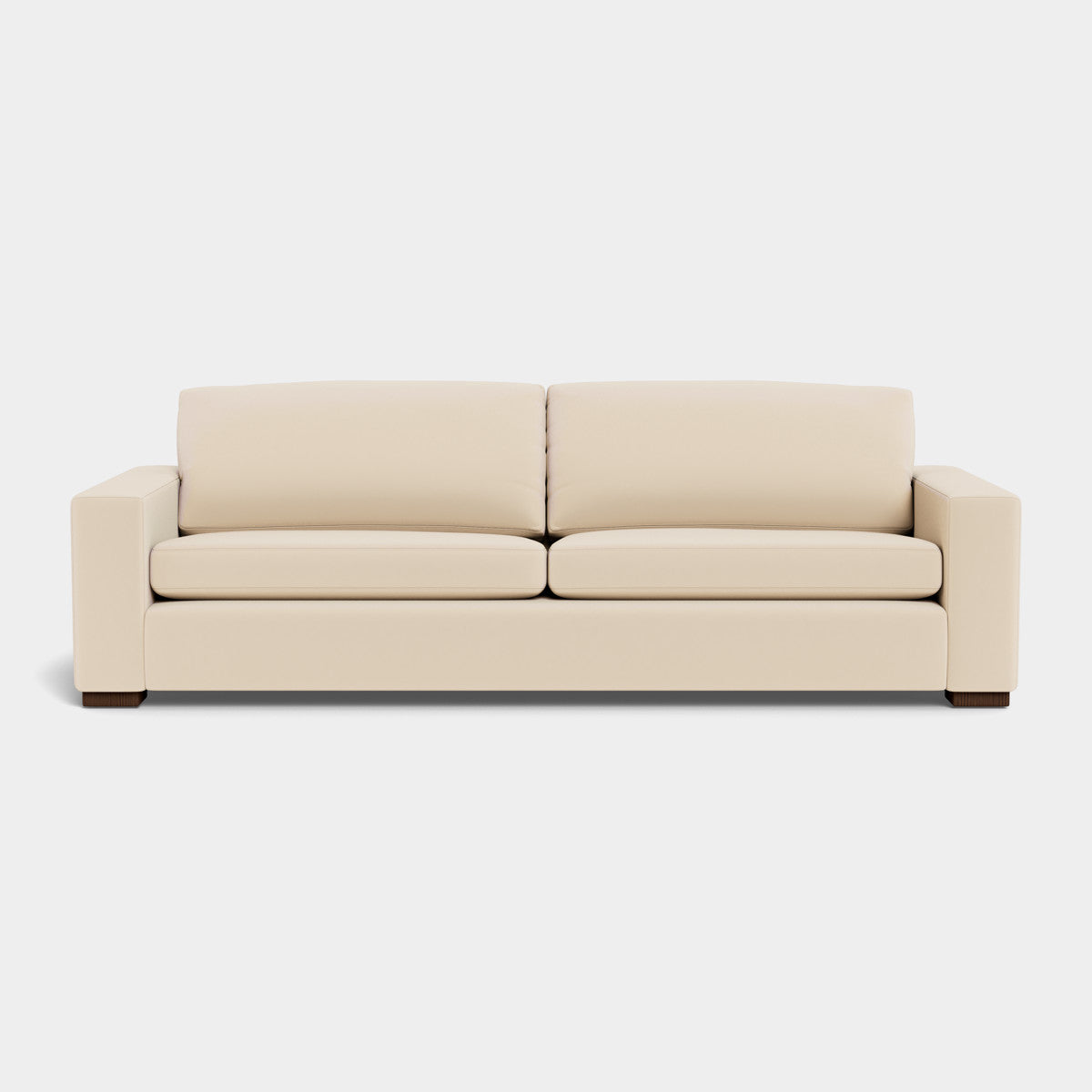 The Barton Sofa is a beige, modern piece with two seat cushions and two back cushions. It boasts a sleek and minimalist design, accentuated by wide armrests and wooden legs, all set against a plain, light background.