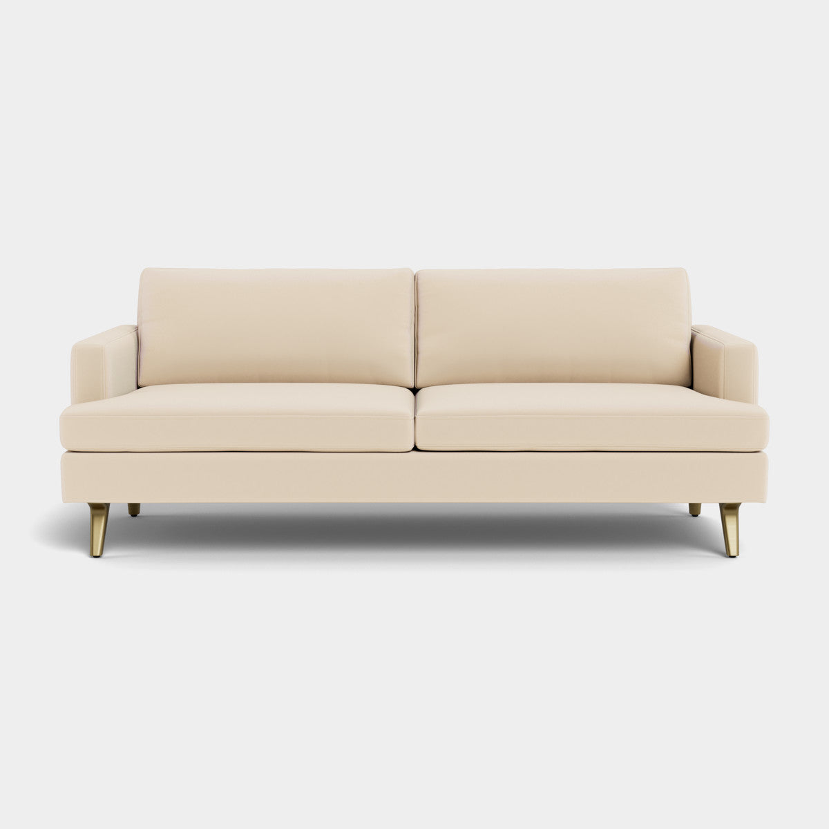 The Lido Sofa, a contemporary beige piece with gold-tipped legs, includes two seat cushions and two backrest cushions, positioned against a simple light backdrop.