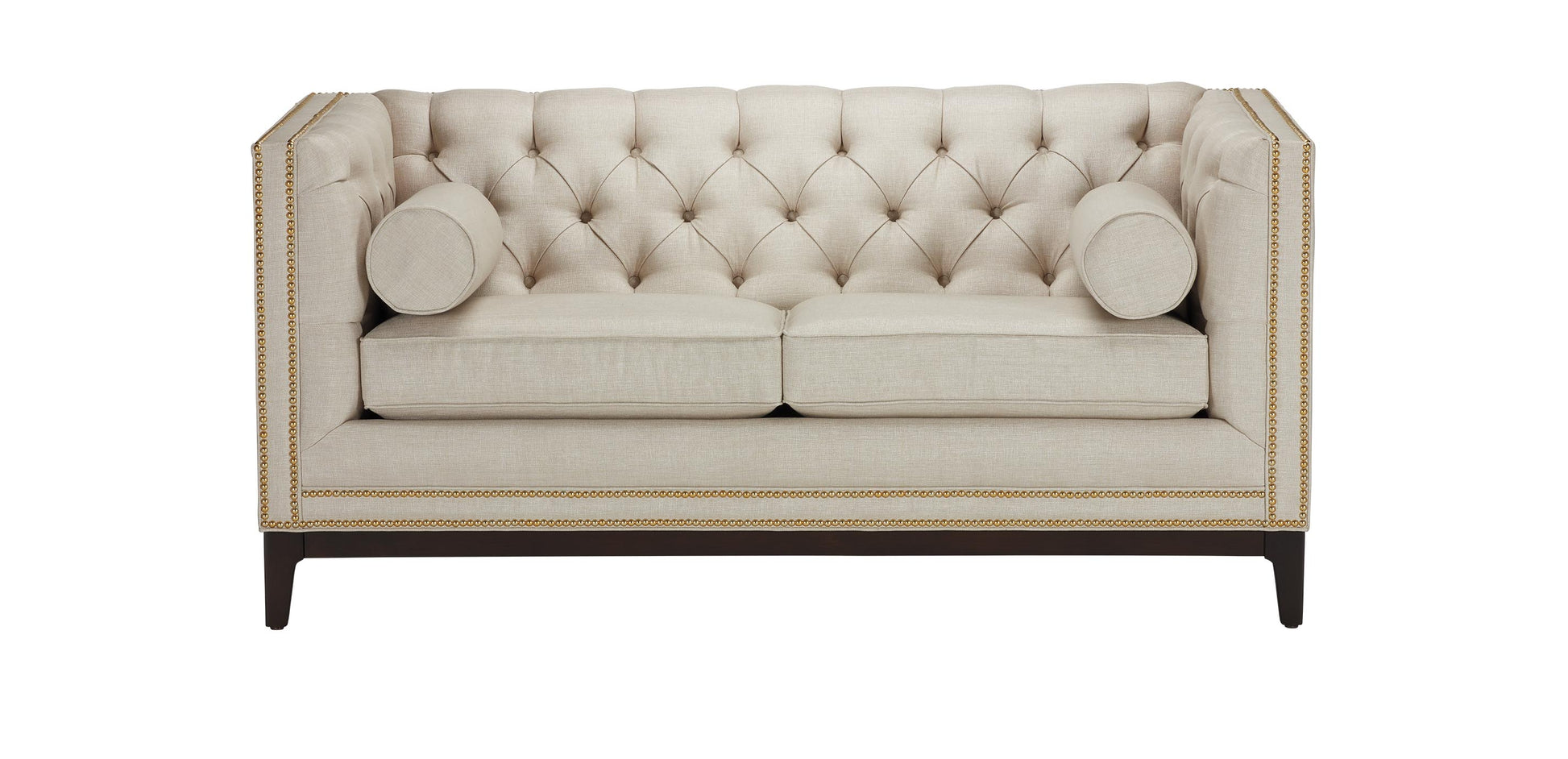 The Anderson Loveseat, in beige with a tufted design and nailhead trim, sits on dark wooden legs. It includes two matching cylindrical bolster pillows on the sides, offering an elegant and sophisticated look.