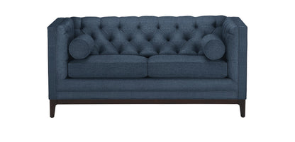 The Anderson Loveseat is a blue, tufted sofa with two cushions on each side. It features dark wooden legs and a boxy design, offering a modern and elegant look.