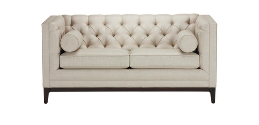 The Anderson Loveseat features a beige tufted design with two seat cushions and two bolster pillows. It has a high back and sides, supported by dark wooden legs.