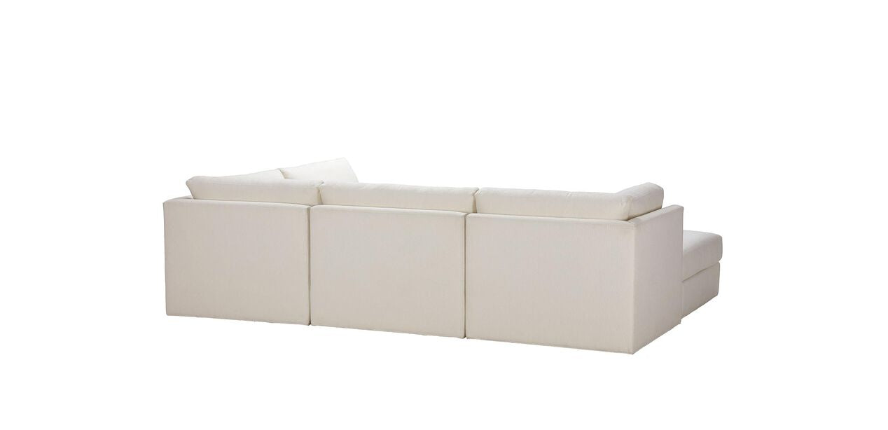 The Daydreamer Modular Six-Piece Sectional is a white sofa featuring three cushioned seats and a chaise lounge on the right, viewed from the back against a plain white background.