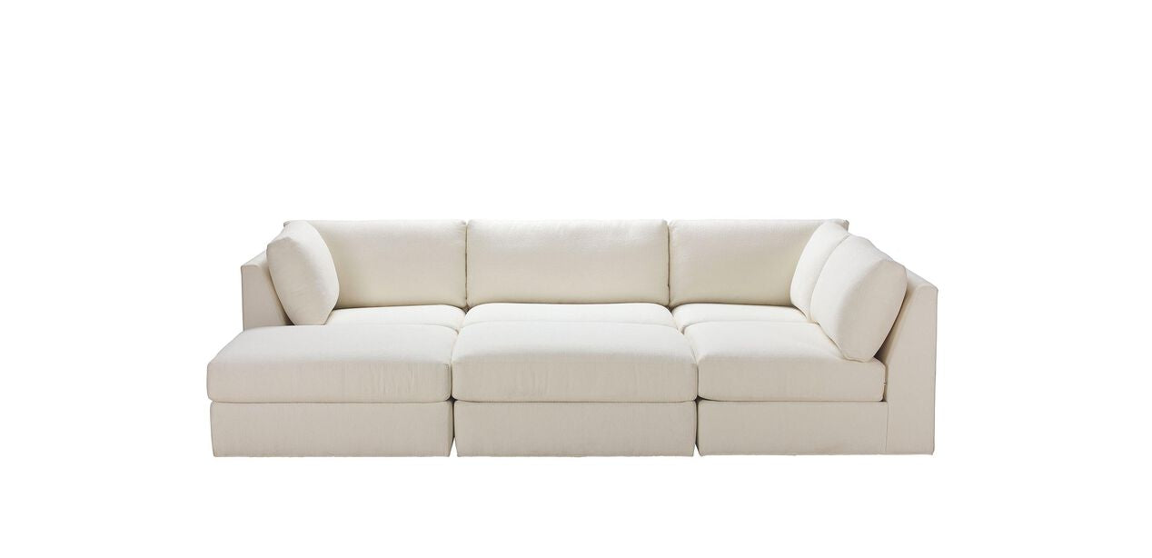 Introducing the Daydreamer Modular Six-Piece Sectional, a contemporary off-white sofa with a sleek minimalist design. It boasts clean lines and plush cushions, with one section extending into a chaise lounge on the left side, set against a simple white background.