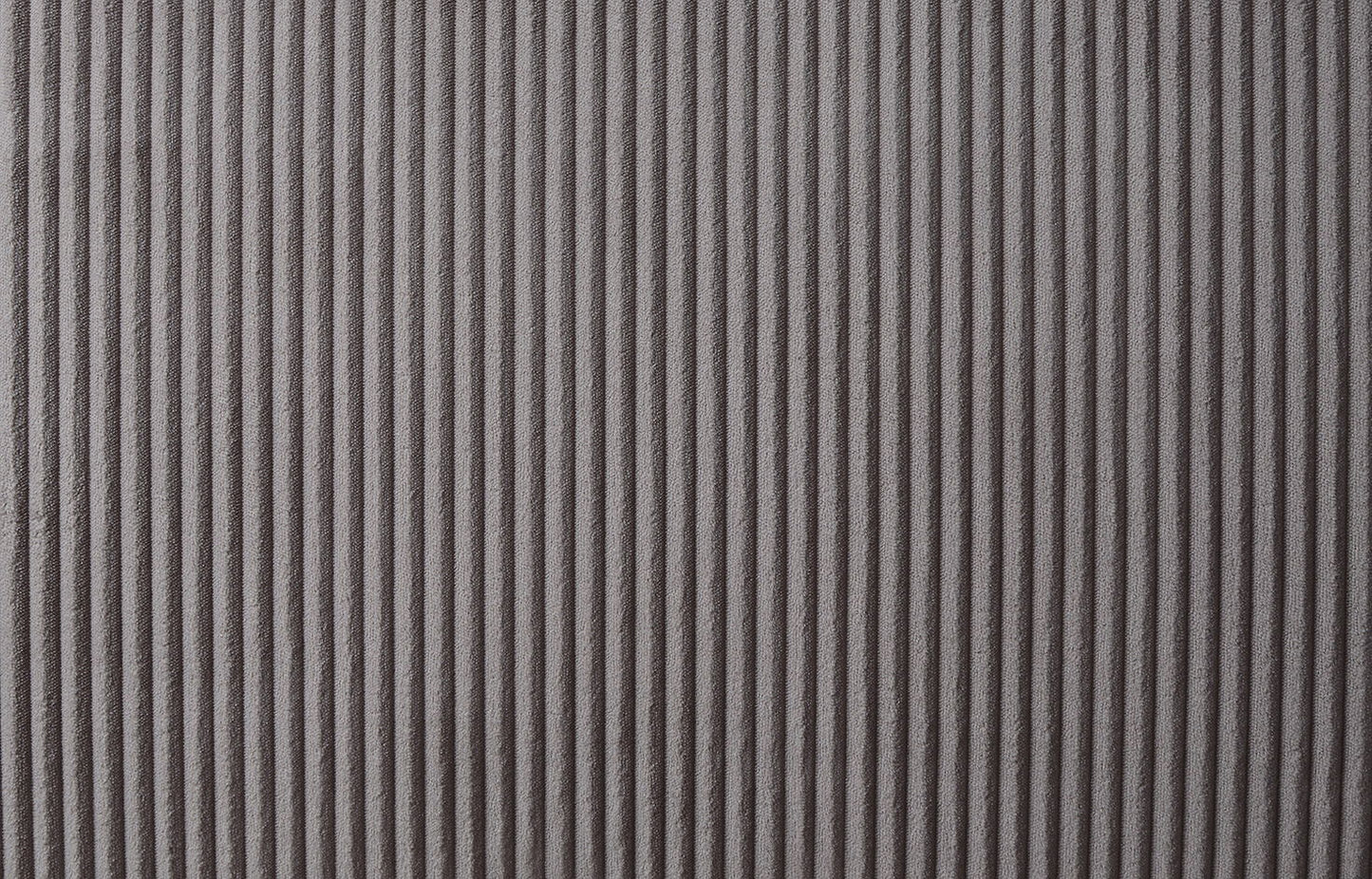 Close-up of a textured surface with vertical ridges in a soft, brown fabric, resembling the Justine Corduroy Convertible Sleeper Loveseat. The ridges cast a pattern of shadows and highlights, enhancing depth and visual interest in the monochromatic design.