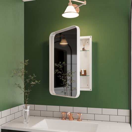 A modern bathroom showcases a green wall adorned with a Recessed Metal Framed Medicine Cabinet With Mirror. Below, there's a white sink featuring copper faucets atop a tiled backsplash. A slender vase with branches rests on the countertop, illuminated by a wall sconce.