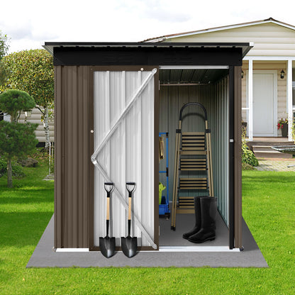 The 5FtX4Ft Outdoor Storage Shed with its door open displays a ladder and shelves inside. Outside, two shovels lean against it, and black boots are at the entrance. The metal shed sits on a grassy lawn near a house.