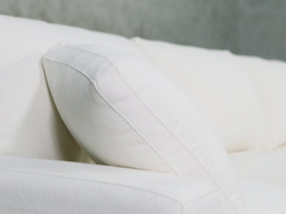 A close-up of a plush white pillow resting on a 3-Seat Modular Chaise Sectional, set against a neutral gray background.