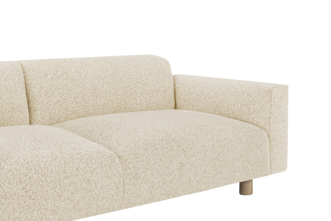 A close-up of the Koti 3-seater Sofa showcases its modern design with textured beige fabric. This sofa features a thick armrest on the right side and is supported by elegant wooden legs. The plush and comfortable seating area makes it an ideal choice for a contemporary living room.