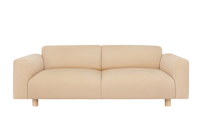 The Koti 2-seater Sofa boasts a minimalist beige design with modern flair, featuring wide armrests and a low profile, supported by short wooden legs and set against a white background.