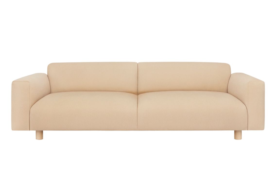 The Koti 3-seater Sofa in beige features a modern design with a low back and wide armrests against a white background. Its clean lines and minimalist aesthetics contribute to its contemporary appearance.