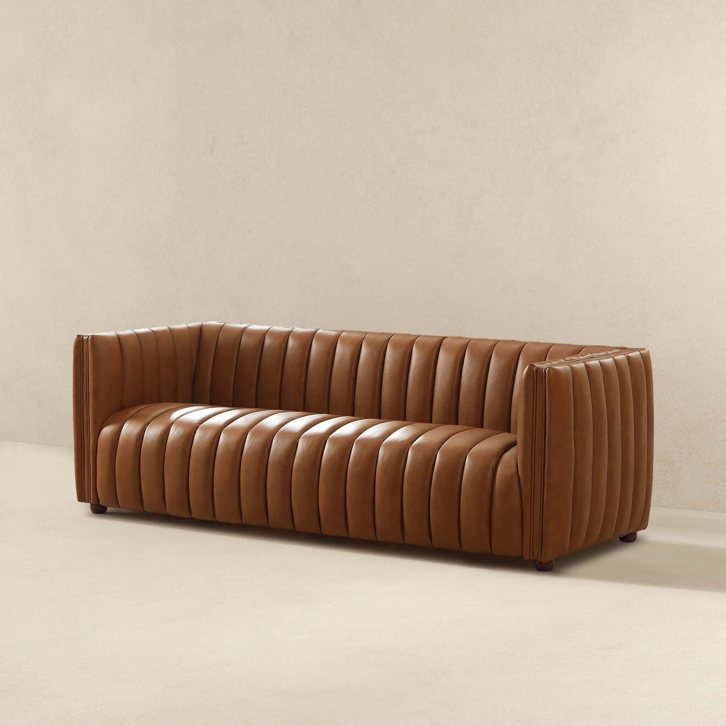 In a minimally decorated room, the April Mid-Century Modern Luxury Tight Back Boucle Couch features modern vertical tufting. This rectangular brown leather sofa with low armrests sits on a light-colored floor against a plain beige wall.