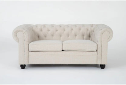 The Elis Wheat 73 Inch Chesterfield Loveseat features a cream color with tufted upholstery, rolled arms, and two seat cushions. It is complemented by dark wooden legs and displayed against a plain white background.