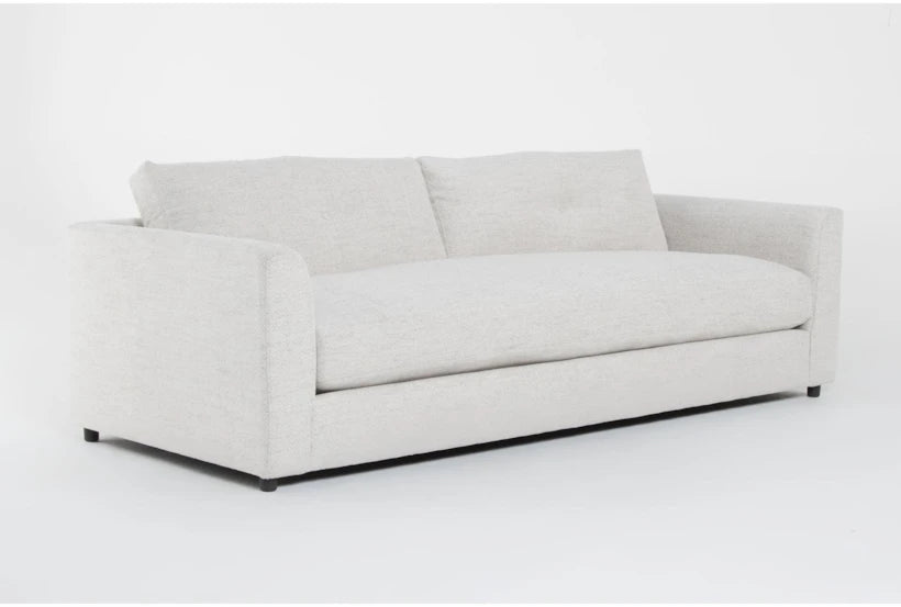 Introducing the Thea Down 101 Inch Beige Chenille Sofa, a contemporary masterpiece with minimalist design elements. This sofa showcases light gray upholstery and flat, rectangular armrests, exuding a clean, sleek appearance perfect for modern home decor. The scene is set against a plain white backdrop.