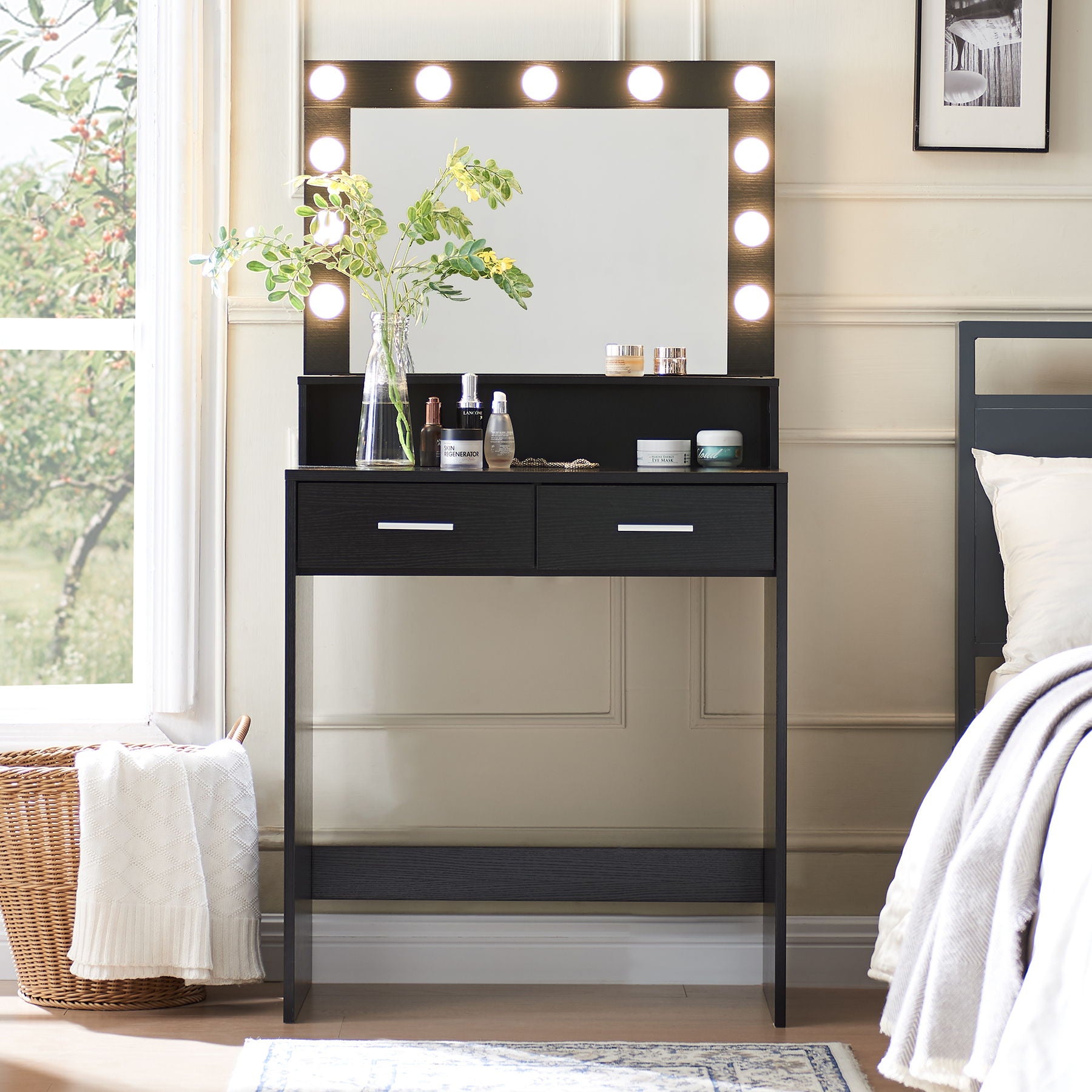 The Vanity Desk with Mirror and Lights stands against a wall, featuring a large drawer and two-tier storage. It holds toiletries and a plant in a vase. A basket with a blanket is nearby, as natural light streams through the window.