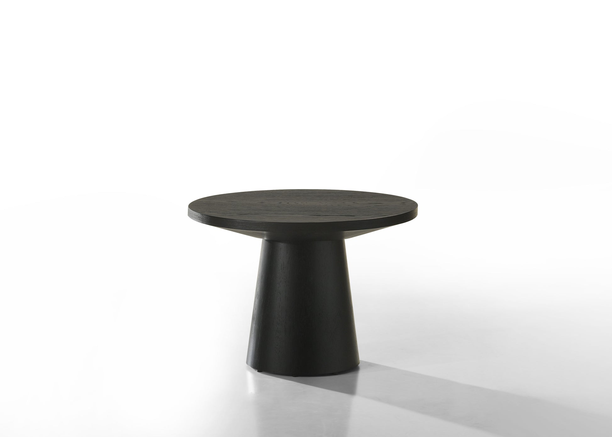 The Jasper - Round Table features a sleek, modern design with a black round top and a conical base, set against a white background.