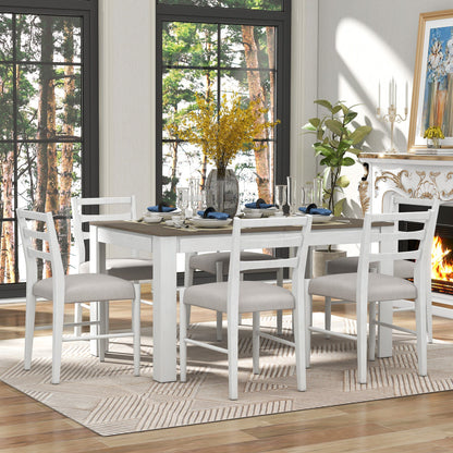 The dining room features a Wooden Dining Table Set with an extendable table and two drawers. It includes cushioned chairs, white plates, and blue napkins. Yellow flowers in a vase sit at the center. Large windows overlook trees outside while a fireplace, art, and candle holders adorn the right wall.