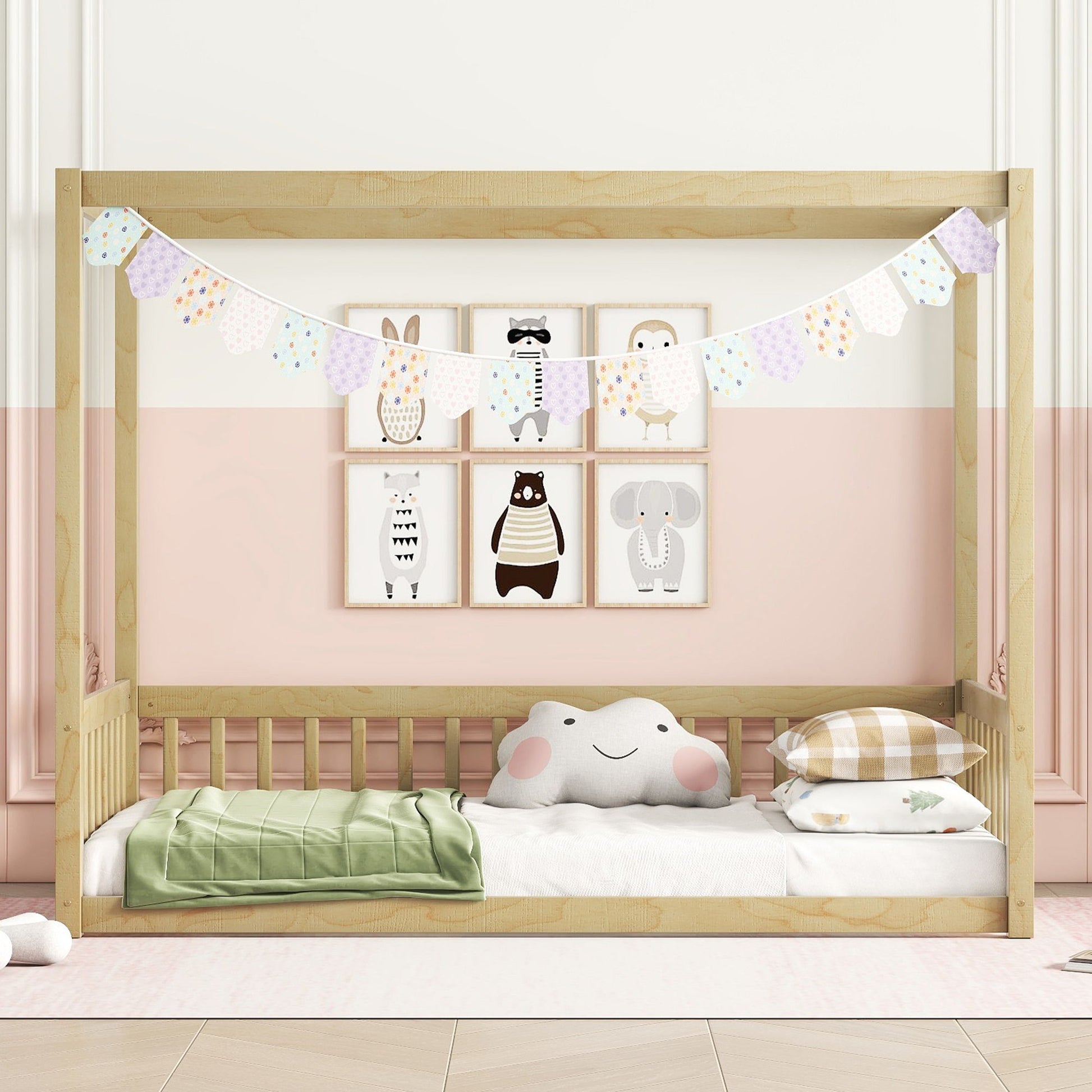 The Canopy Frame Floor Bed With Fence and Guardrails features a wooden design with pastel bunting, playful animal wall art, a smiling cloud pillow, plaid and green blankets on a light pink background.