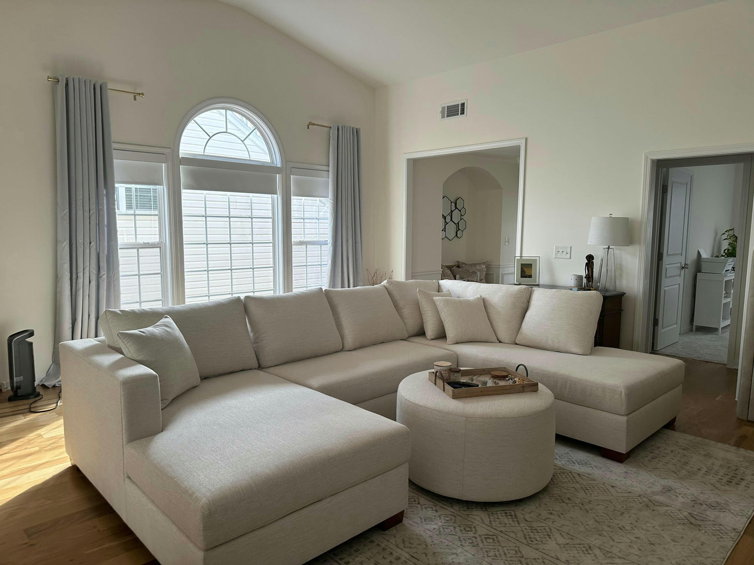 White U-shaped sectional in a living room. A circular ottoman with a tray is in the middle of the U. 