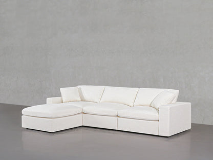 A 4-Seat Modular Chaise Sectional in sleek white, featuring clean lines and plush cushions, is displayed against a simple gray background. This sofa includes a left-side chaise, providing a roomy and comfortable seating area.