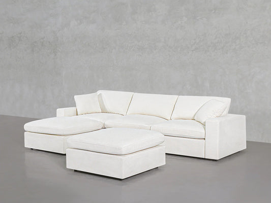 A modern 4-seat modular chaise sectional with an ottoman is set against a minimalist gray wall and floor, featuring clean lines and plush cushions.